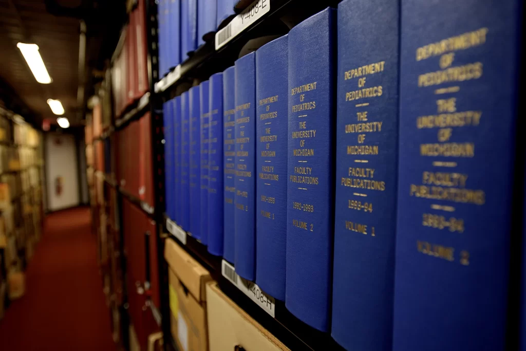 Several blue books lining a shelf in the stacks of the Bentley Historical Library.