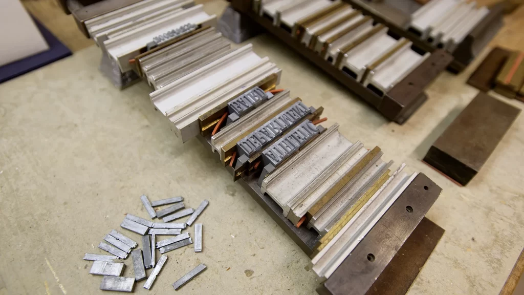 A close-up view of typeface letters from U-M's historical book bindery which are used in the Bentley Historical Library's Conservation Lab, including some letters that are very small, and some that are very large, on a beige table.