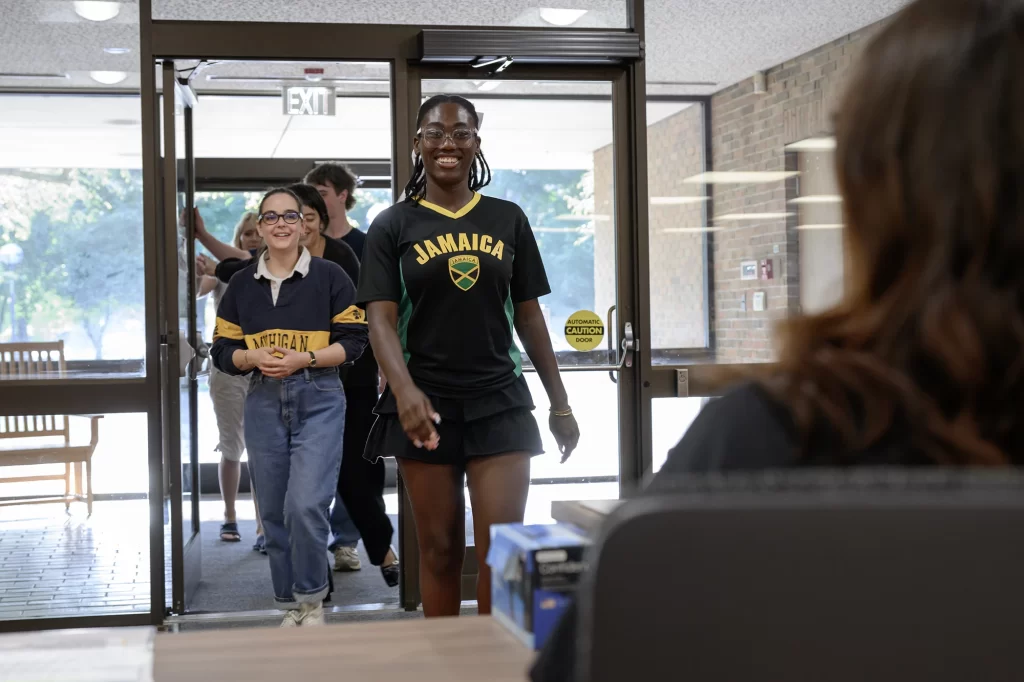 Several young visitors walk through the front door of the Bentley Historical Library toward the welcome desk. The back of the head of the person sititng at the desk is visible.