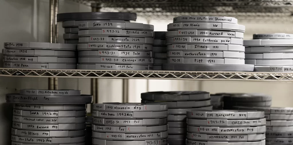 Historical film reels stacked on white metal shelves in the Bentley Historical Library's Cold Room.