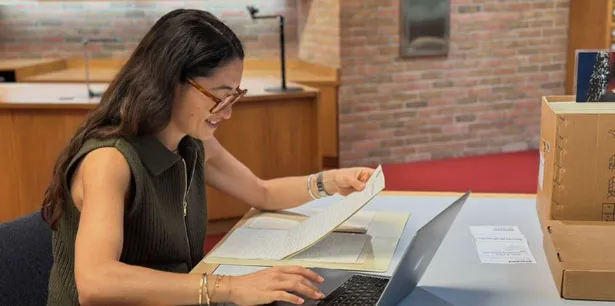 A researcher seated at a table in the Bentley's reading room with papers and a laptop.